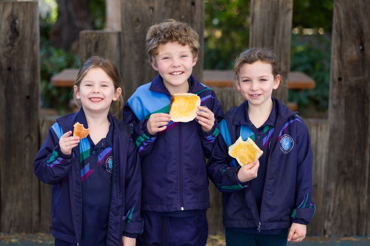 three students eating toast