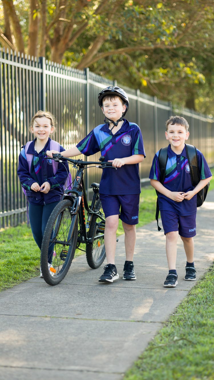 Three students walking to school. One student is pushing a bike.