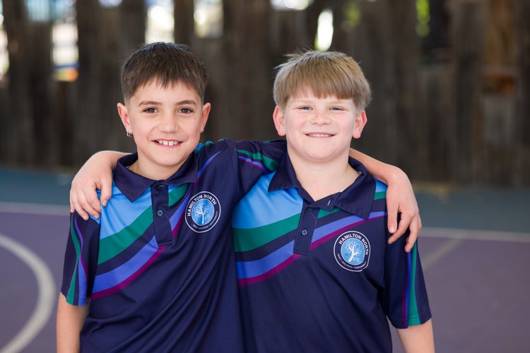 Two boy students with arms around each other.